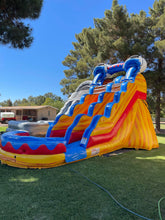 Load image into Gallery viewer, An inflatable water slide with blue, yellow, and red colors set up outdoors on a grassy area.
